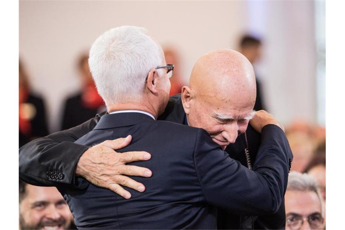 Heinrich Riethmüller (l), Vorsteher des Börsenvereins des Deutschen Buchhandels, umarmt Sebastião Salgado nach seiner Rede in der Paulskirche. Foto: Andreas Arnold/dpa