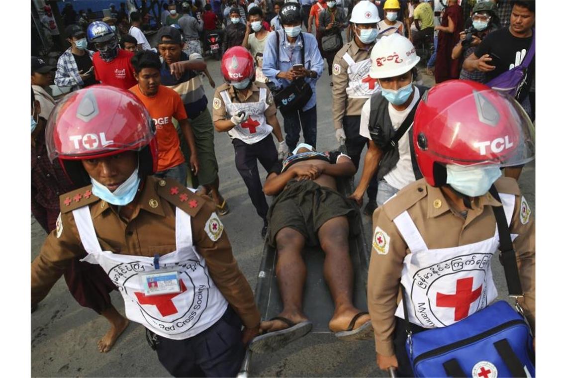 Medien: Mindestens zwei Tote bei Protesten in Myanmar Helfer des Roten Kreuzes tragen einen Verletzten von einer Demonstration gegen den Putsch weg. Foto: --/AP/dpa