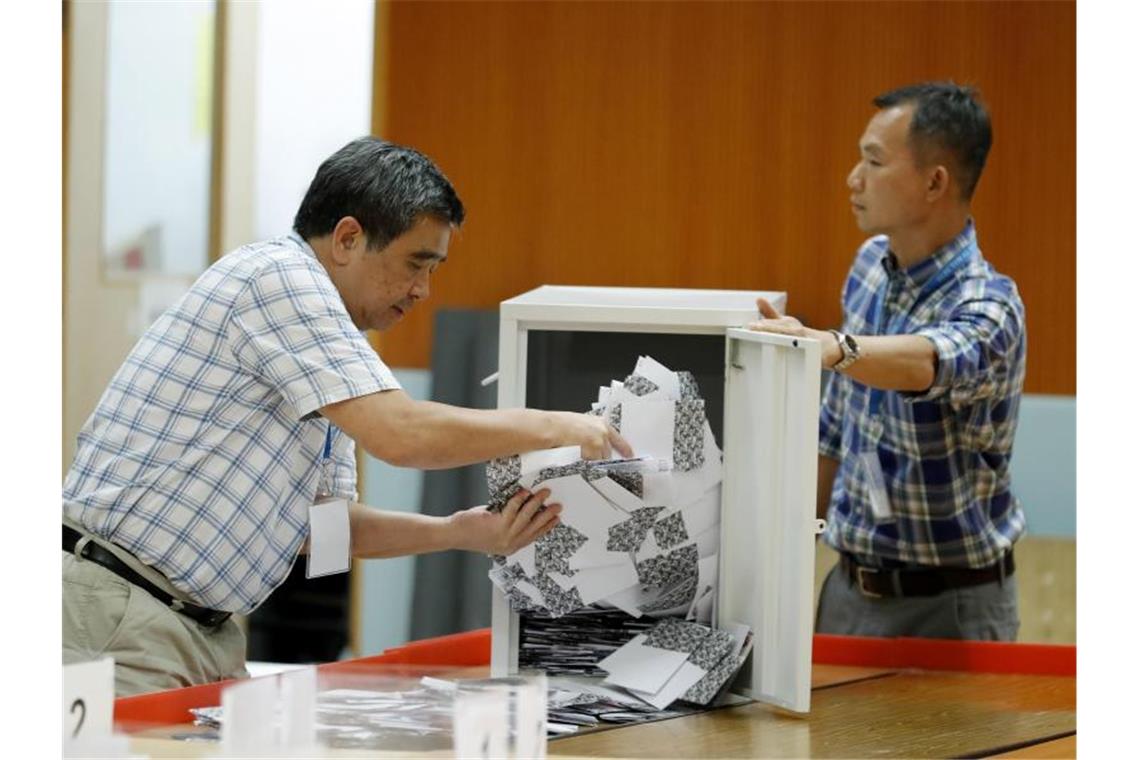 Helfer leeren eine Wahlurne. Foto: Vincent Thian/AP/dpa