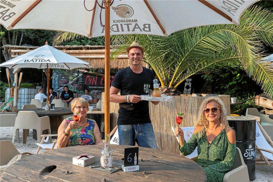 Helga und Sylvia Wörner (von links) sind aus Korb gekommen, um den Abend am „Cocoloco Beach“ zu genießen. Mike Isert serviert ihnen einen Aperitif. Foto: J. Fiedler