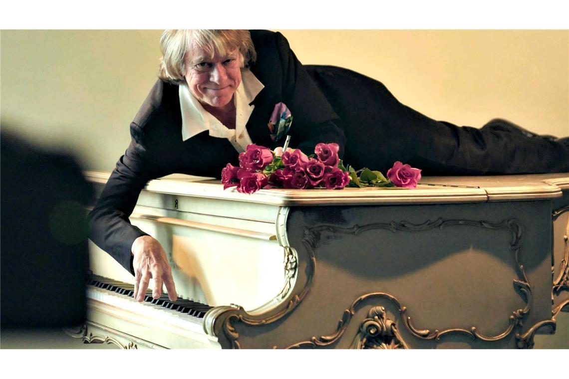 Helge Schneider liegt auf einem Klavier in einer Szene des Films "Helge Schneider - The Klimperclown", der nun in der Mediathek zu sehen ist und am Mittwoch, 20.8., im Ersten gezeigt wird.