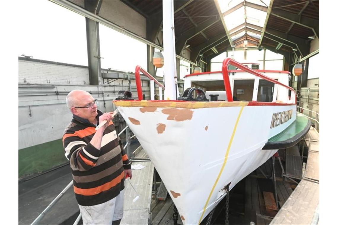 Ausflugsschiff „Reichenau“ zum Schönmachen in der Werft Henry von Hoff, Mitarbeiter der Bodensee Schiffsbetriebe (BSB), bessert mit dem Pinsel den Bug des Motorschiffs Reichenau aus, das in der Werft für die Saison hergerichtet wird. Foto: Felix Kästle/dpa/Archivbild