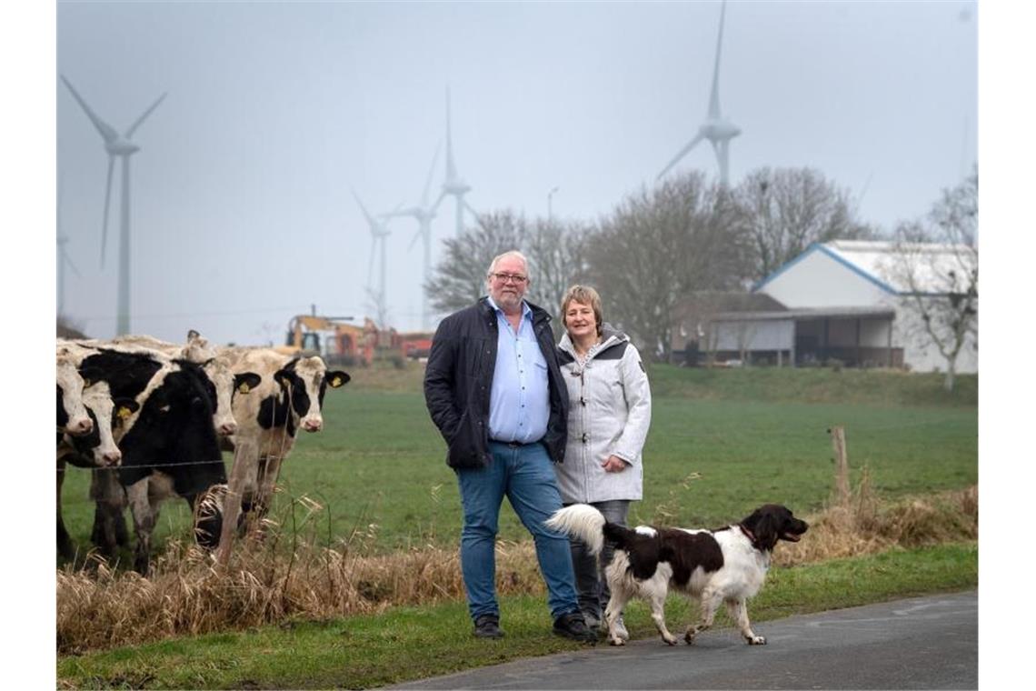 Hermann Oldewurtel und Insa Bock stehen vor den Windkraftanlagen hinter ihrem Wohnhaus in Holtgast. Foto: Sina Schuldt/dpa