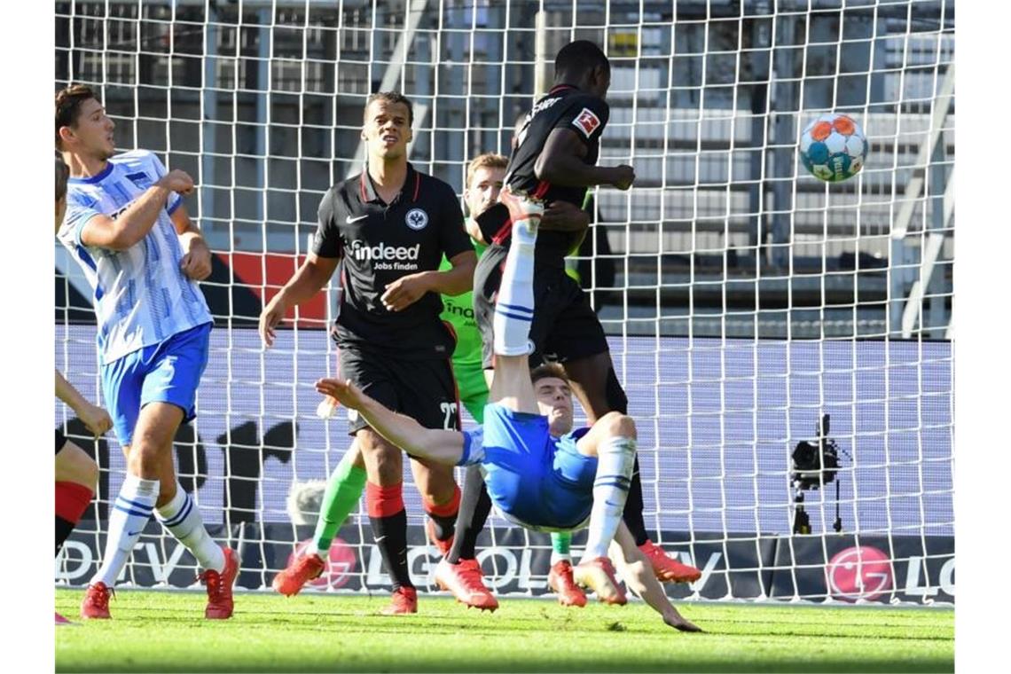 Herthas Krzysztof Piatek (M) versucht sich gegen Frankfurts Evan Ndicka mit einem Fallrückzieher. Foto: Arne Dedert/dpa