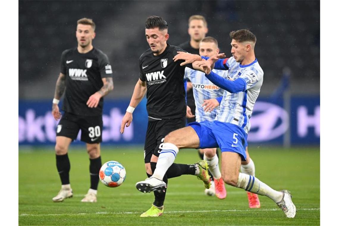 Bayern müht sich - BVB zeigt Reaktion nach Königsklassen-Aus Herthas Niklas Stark (r) und Augsburgs Andi Zeqiri (M) kämpfen um den Ball. Foto: Soeren Stache/dpa-Zentralbild/dpa