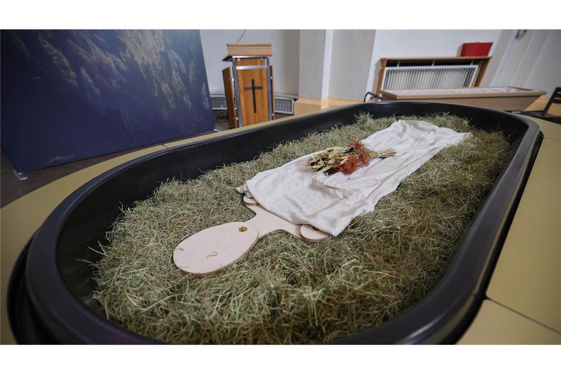 Heu, Stroh, Blumen und eine Holzfigur liegen in einer Kapelle in Kiel einem sogenannten Kokon für eine Reerdigung, eine alternative Bestattungsform.