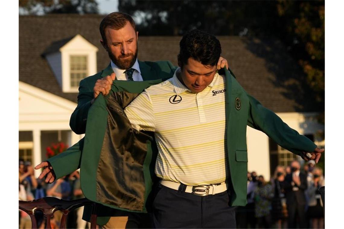 Hideki Matsuyama zieht sich mit Hilfe von Dustin Johnson das legendäre grüne Sieger-Jackett an. Foto: David J. Phillip/AP/dpa