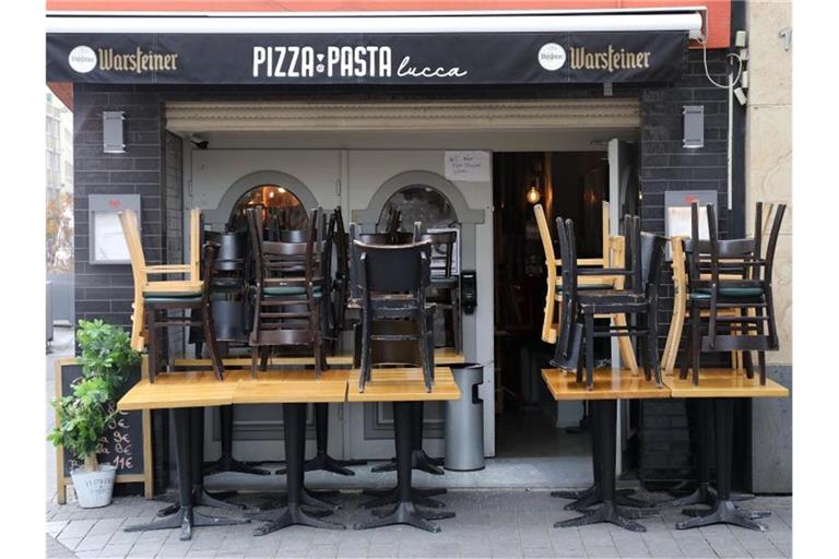 Hier darf man nicht essen: Vor einem Restaurant in Köln stehen die Stühle coronabedingt auf den Tischen. Foto: Oliver Berg/dpa