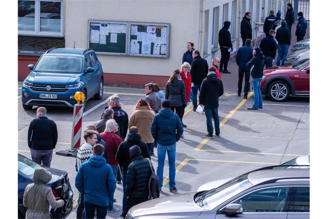 Corona-Krisenmaßnahmen: Vorerst keine Lockerung Hier ist Geduld gefragt: Apotheker und Mitarbeiter von Versorgungsbetrieben stehen auf dem Gelände des Zuckerwerks in Anklam in einer langen Schlange am Verkaufsbüro an. Foto: Jens Büttner/dpa-Zentralbild/dpa