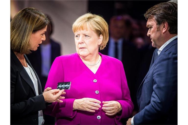 Hildegard Wortmann, Vorstand Audi, Bundeskanzlerin Angela Merkel (CDU) und Audi-Chef Bram Schot beim Eröffnungsrundgang auf der IAA am Stand von Audi. Foto: Andreas Arnold/dpa