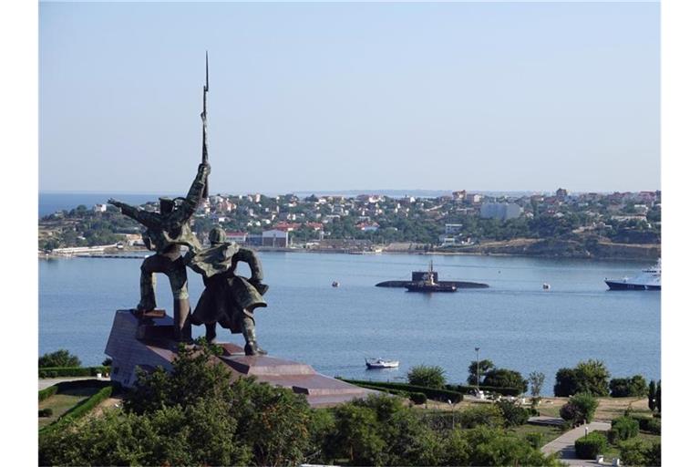 Hinter dem sowjetischen Denkmal „Soldat und Seemann“ liegen ein U-Boot und Kriegsschiffe der russischen Schwarzmeerflotte vor Anker in der Hafenstadt Sewastopol. Foto: Ulf Mauder/dpa