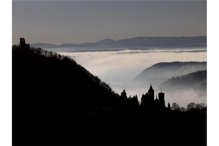 Hinter Schloss Drachenburg (r) und der Burg Drachenfels ziehen Nebelschwaden durch das Rheintal. Foto: Oliver Berg/dpa