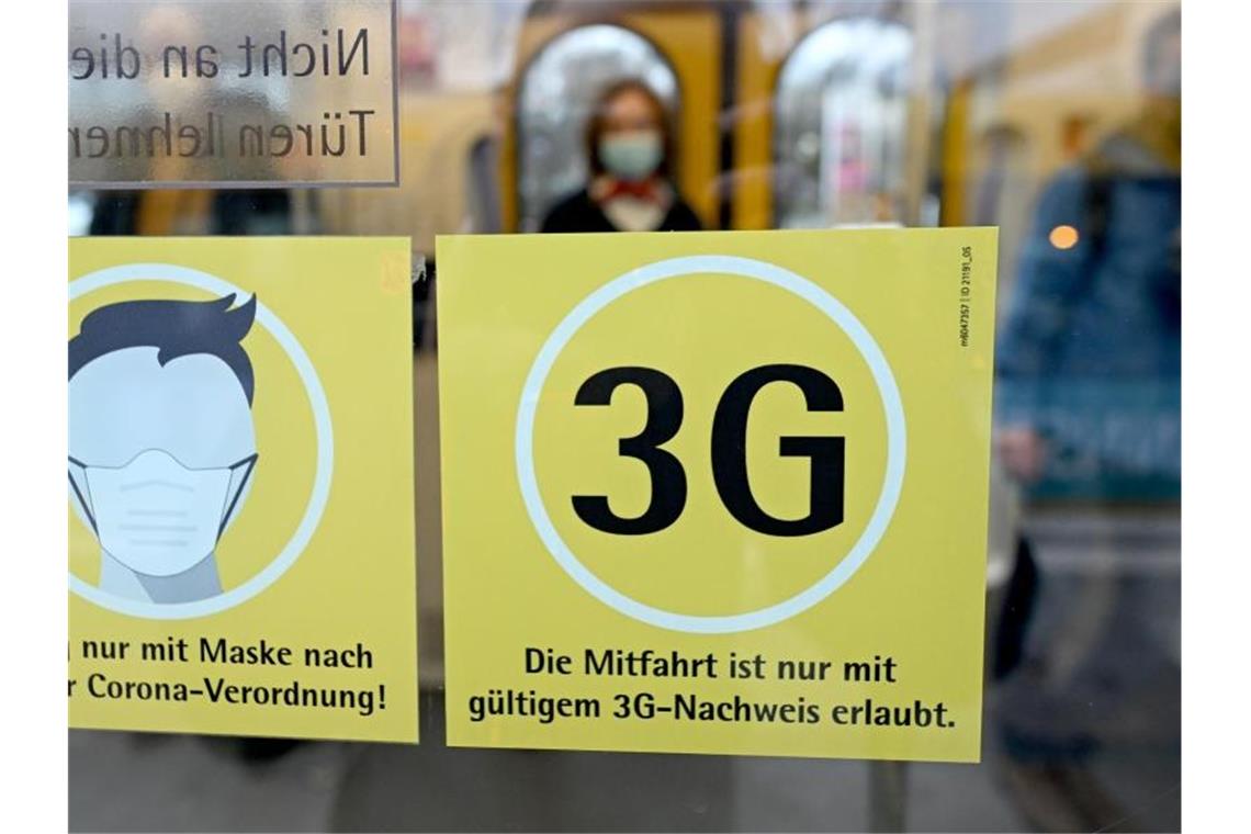 Hinweisschilder für die Maskenpflicht und die 3G-Regeln hängen am Fenster einer U-Bahn. Foto: Bernd Weißbrod/dpa/Archivbild