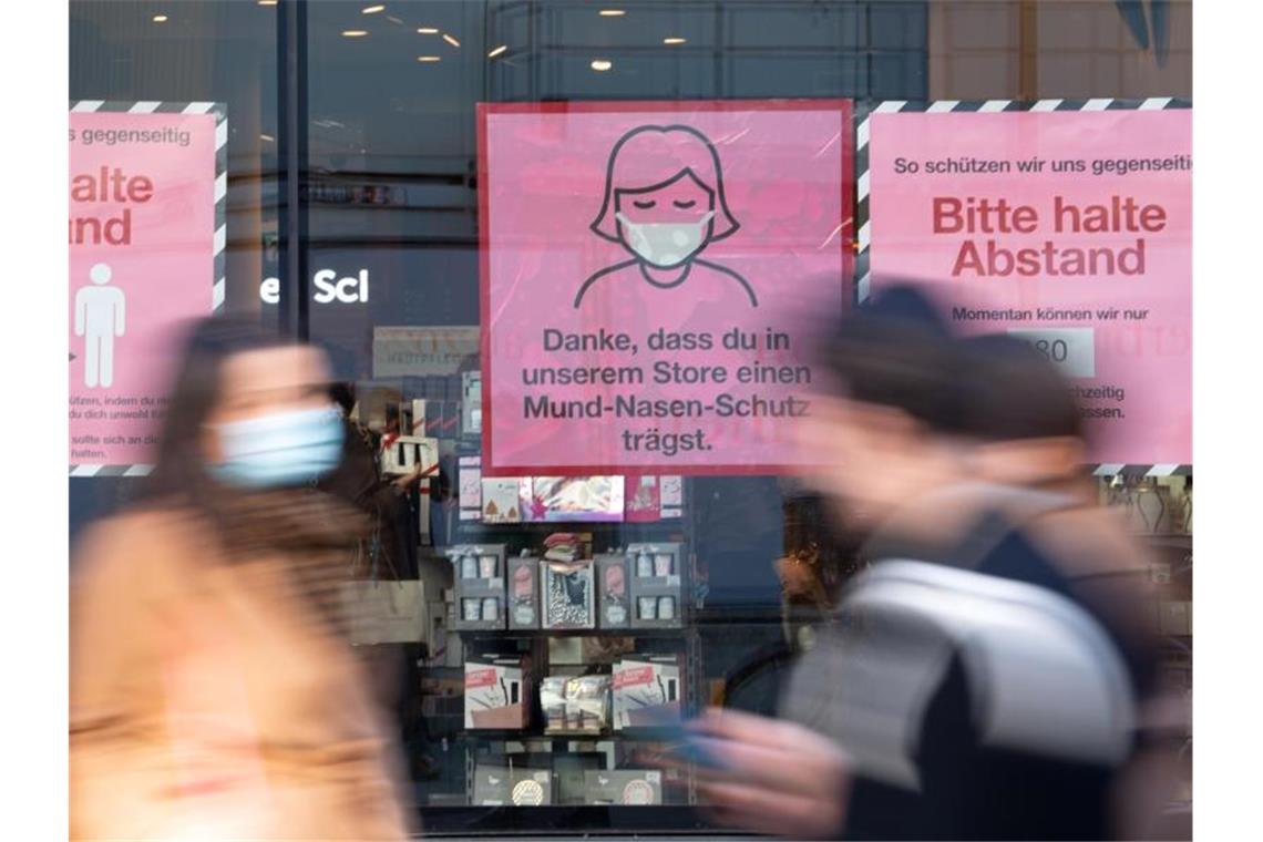 Hinweisschilder zum Corona-Schutz an einem Schaufenster in der Innenstadt von München. Foto: Sven Hoppe/dpa