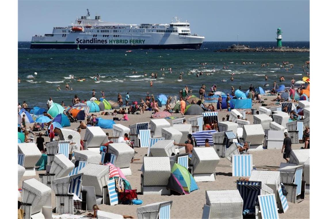 Hochbetrieb am Ostseestrand von Warnemünde, während im Hintergrund die Scandlines-Fähre „Copenhagen“ einläuft. Foto: Bernd Wüstneck