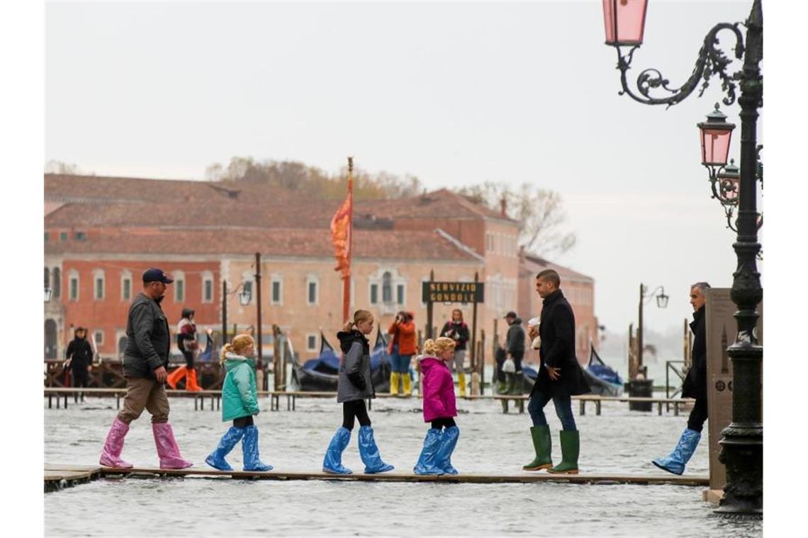 Hochwasser-Routine in Venedig: Touristen sind auf schmalen Stegen unterwegs. Foto: Luca Bruno/AP/dpa