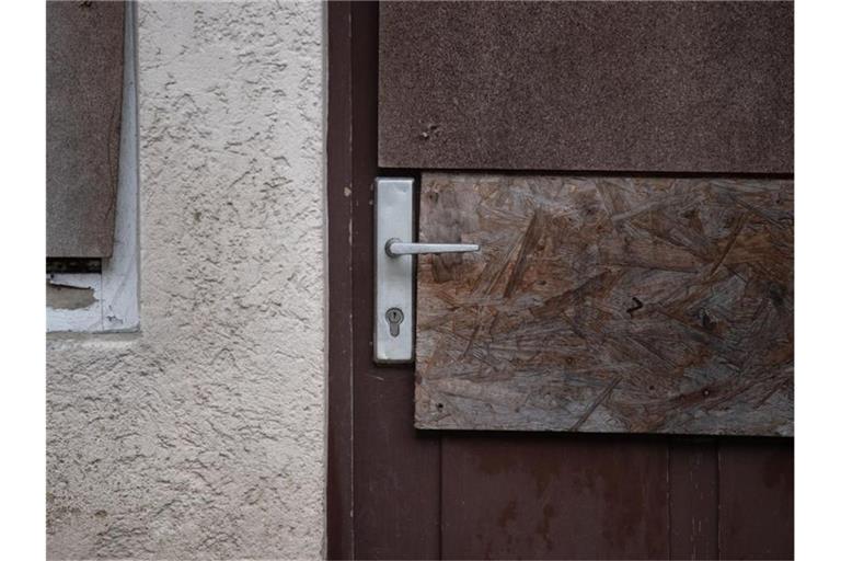 Holzplatten sind an einer Tür und einem Fenster eines unbewohnten Hauses angebracht. Foto: Marijan Murat/dpa