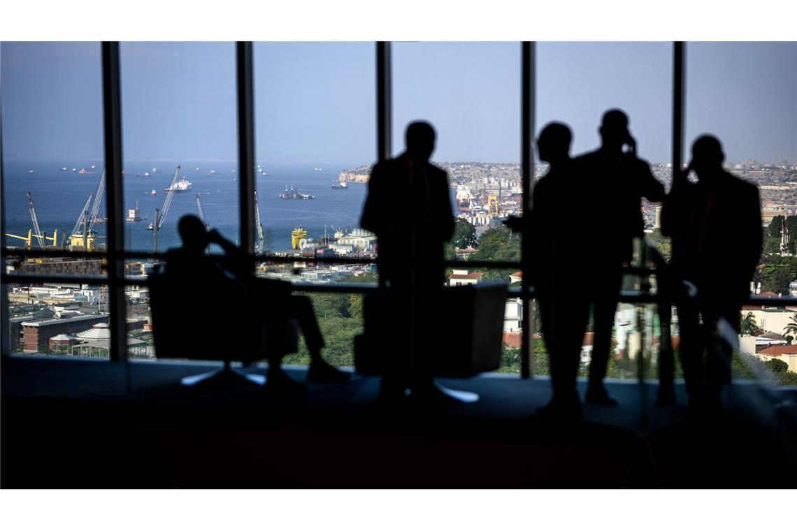 Hotelgäste stehen zum Teil telefonierend vor einem Panoramafenster in einem Luxushotel in Luanda.