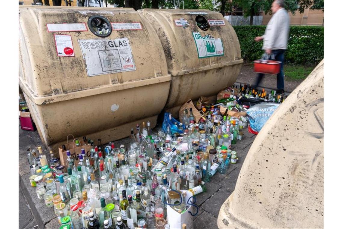 Hunderte Glasflaschen stehen neben vollen Containern am Strassenrand im Stadtteil Haidhausen in München. Foto: Peter Kneffel/dpa