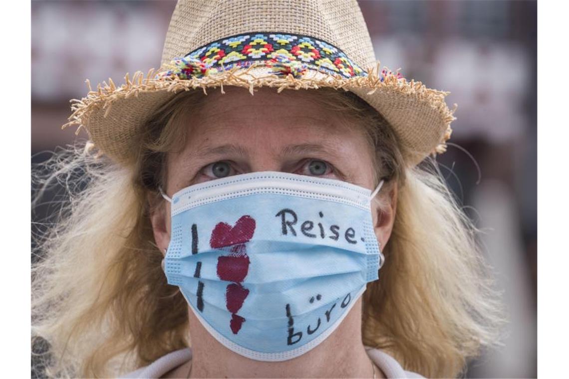 "Ich liebe Reisebüros" steht auf dem Mundschutz einer Demonstrantin. Foto: Frank Rumpenhorst/dpa