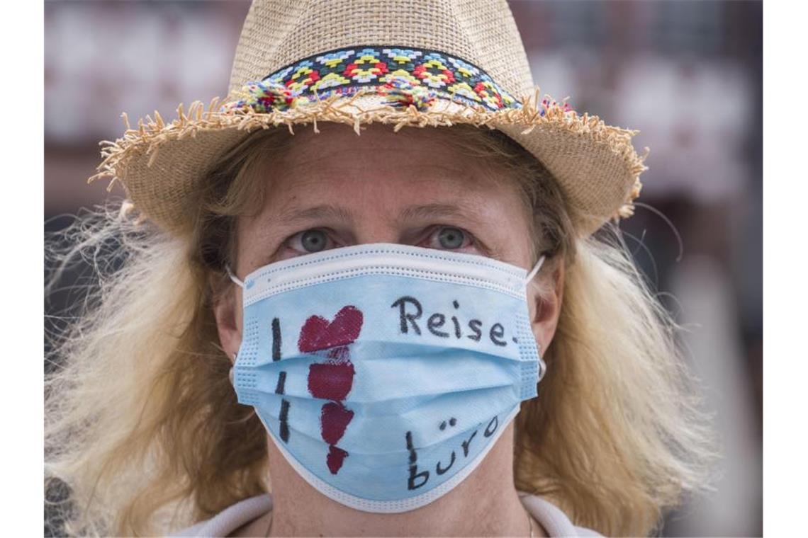 Reisebüros und Busunternehmer fordern Rettungsschirm "Ich liebe Reisebüros" steht auf dem Mundschutz einer Demonstrantin. Foto: Frank Rumpenhorst/dpa