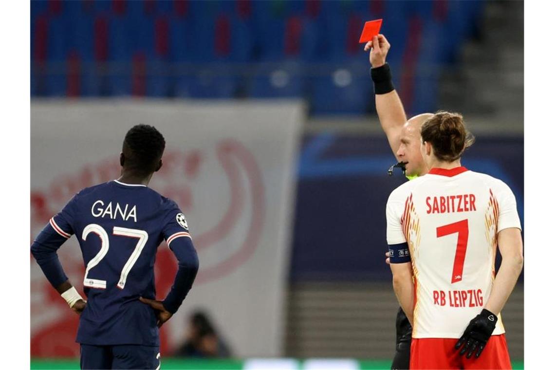 Idrissa Gana Gueye (l) von PSG bekommt die Rote Karte von Schiedsrichter Szymon Marciniak (M, neben Marcel Sabitzer/7). Foto: Jan Woitas/dpa-Zentralbild/dpa