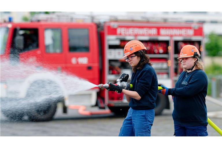 Ilias (links) und Annabella, Mitglieder der Jugendfeuerwehr in Mannheim, halten bei einer Übung einen Feuerwehrschlauch in den Händen.