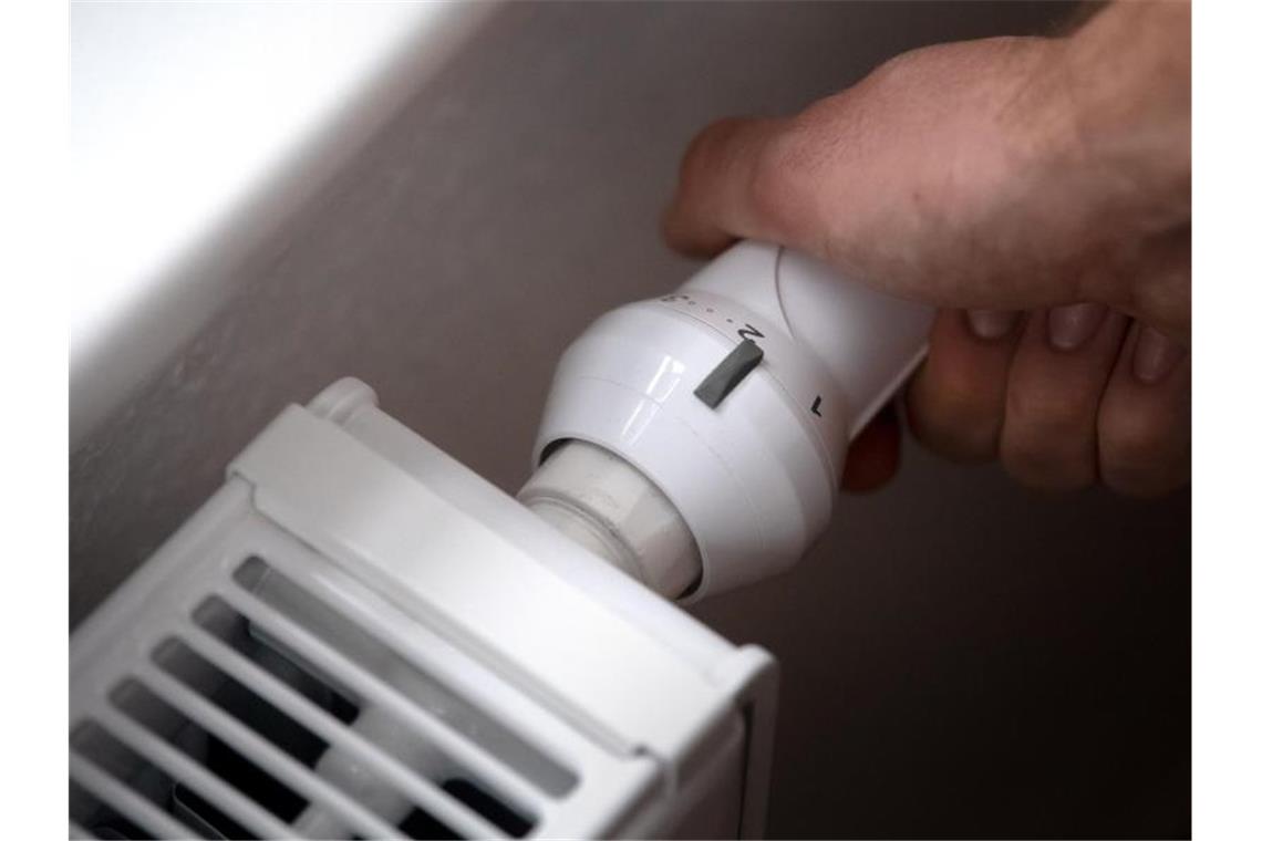 Gaspreise auf Höhenflug: Verbrauchern droht teurer Winter ILLUSTRATION - Ein Mann dreht am Thermostat einer Heizung. Die Großhandelspreise für Erdgas steigt und steigt. Foto: Sina Schuldt/dpa