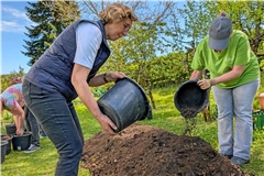 Ilse Mann (links) und Martina Stark schütten die letzten Eimer mit aufgelockerter Erde aufs aufbereitete Hügelbeet. Foto: Carolin Aichholz