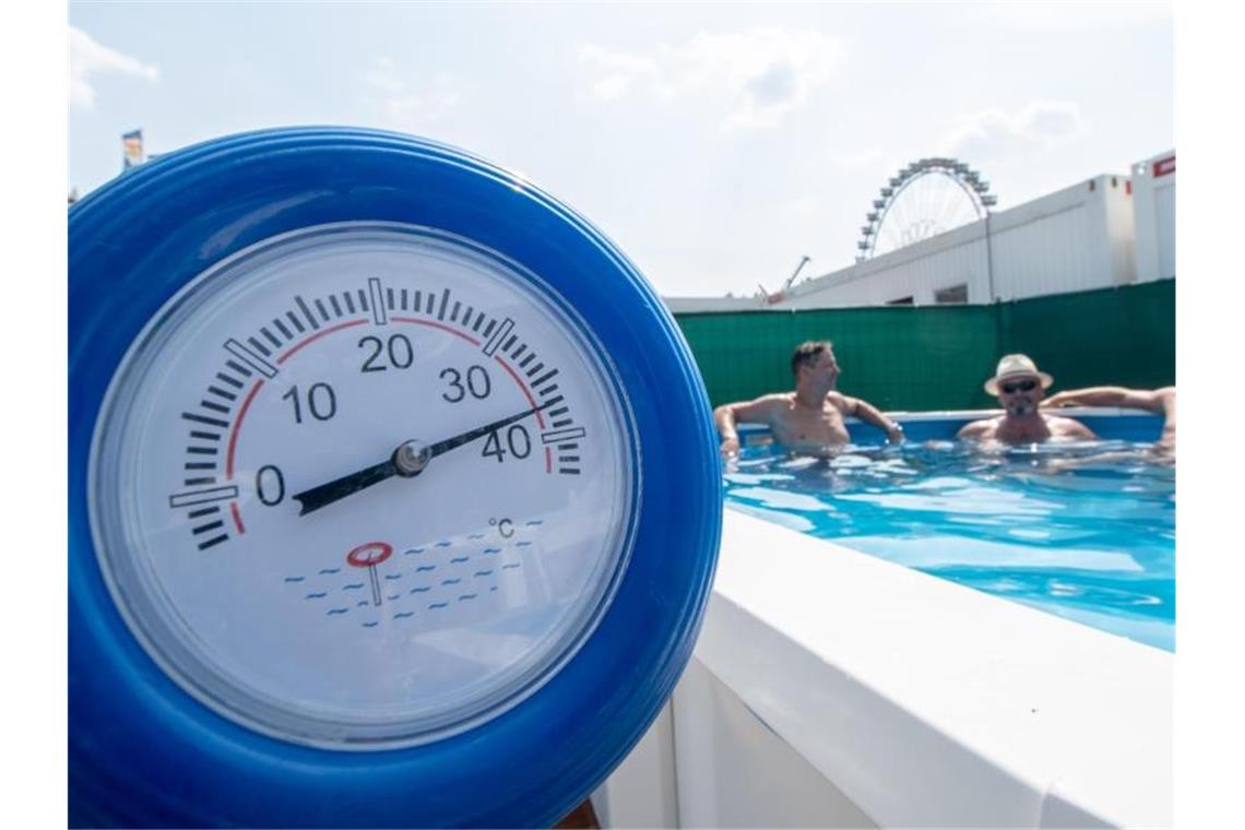 Extreme Junihitze - Wetterrekorde verlagern sich nach vorn Im bayerischen Straubing zeigt ein Thermometer schon 38 Grad an, während sich die Monteure eines Messestands für Pools während einer Pause auf dem Gelände der Ostbayernschau abkühlen. Foto: Armin Weigel