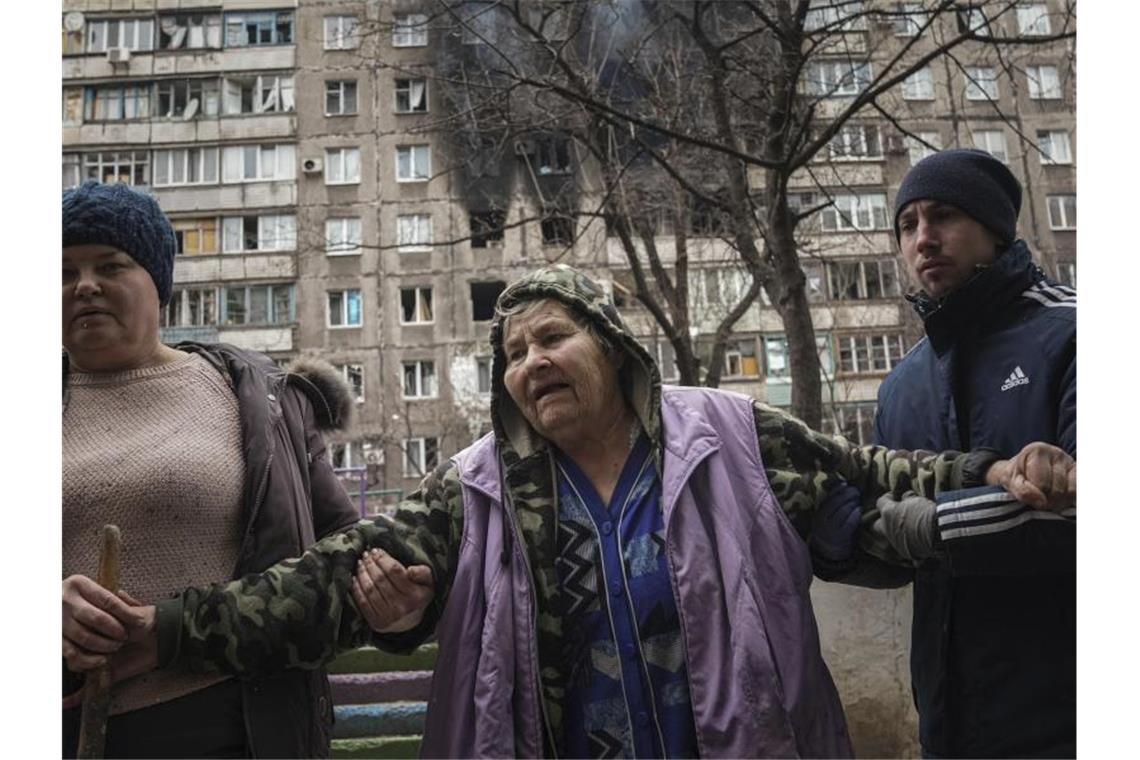 Krieg gegen die Ukraine: Das ist die Lage am Abend Im Hintergrund ein von Granaten getroffenes Haus. Die Lage in der eingekesselten Stadt Mariupol spitzt sich immer weiter zu. Separatisten sollen abermals vorgerückt sein. Foto: Evgeniy Maloletka/AP/dpa
