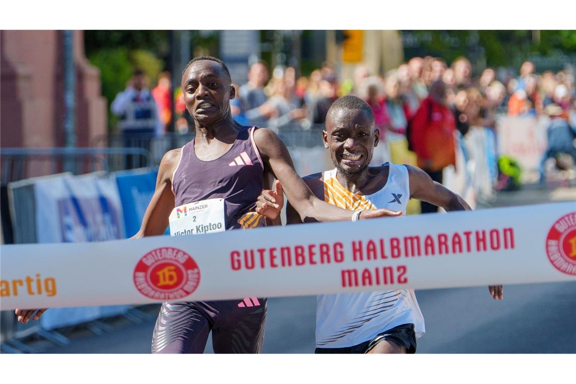 Im letzten Moment gleichauf: Victor Kiptoo (l, Uganda) und Benson Nzioki (Kenia) kommen beim Gutenberg-Halbmarathon in Mainz zur gleichen Zeit ins Ziel und teilen sich nach derzeitigem Stand den ersten Platz.