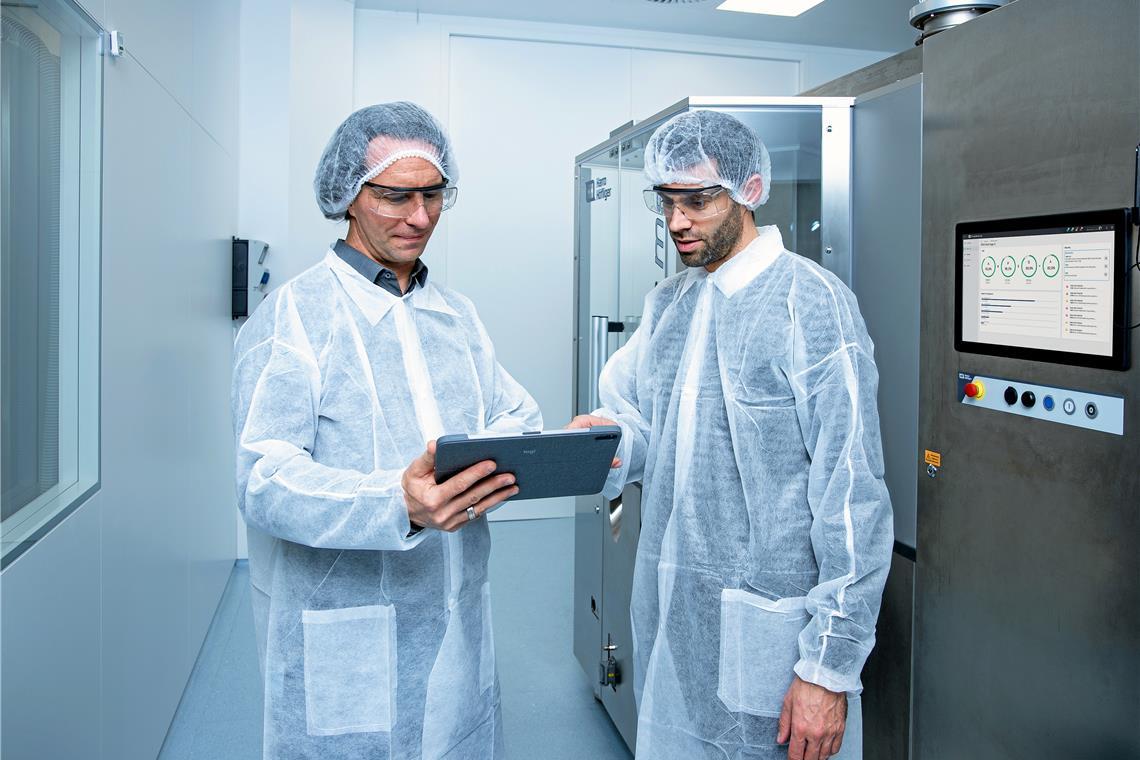 KI bei Höfliger erkennt Fehler, bevor sie auftreten Im Reinraum von Harro Höfliger testen Falk Pfitzer (links) und Tobias Miunske eine Produktionsanlage. Aus Hunderten von Echtzeitdaten ermittelt eine App vier Leistungswerte, die als Prozentzahlen auf dem Display an der Maschine angezeigt werden. Fotos: Harro Höfliger