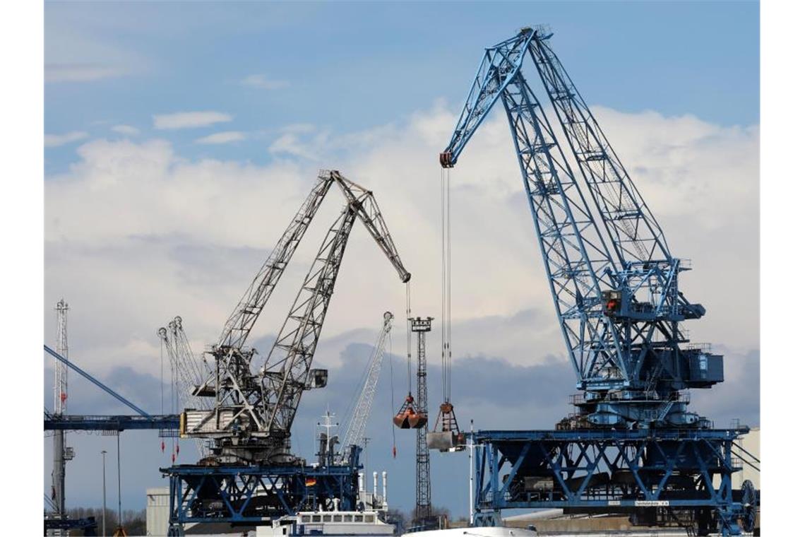 Wirtschaftsinstitute senken Konjunkturprognose Im Seehafen an der Ostsee wird ein Schiff mit Kränen abgefertigt. Foto: Bernd Wüstneck/dpa