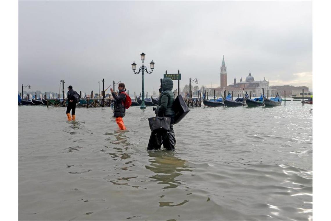 Immer auf den Wegen bleiben: Menschen waten unweit des Ufers zum „Bacino San Marco“ durchs überflutete Venedig. Foto: Andrea Merola/ANSA/AP/dpa