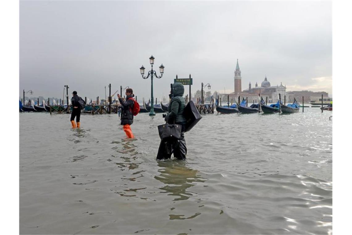 „Apokalyptische Zerstörung“: Hochwasser verwüstet Venedig Immer auf den Wegen bleiben: Menschen waten unweit des Ufers zum „Bacino San Marco“ durchs überflutete Venedig. Foto: Andrea Merola/ANSA/AP/dpa