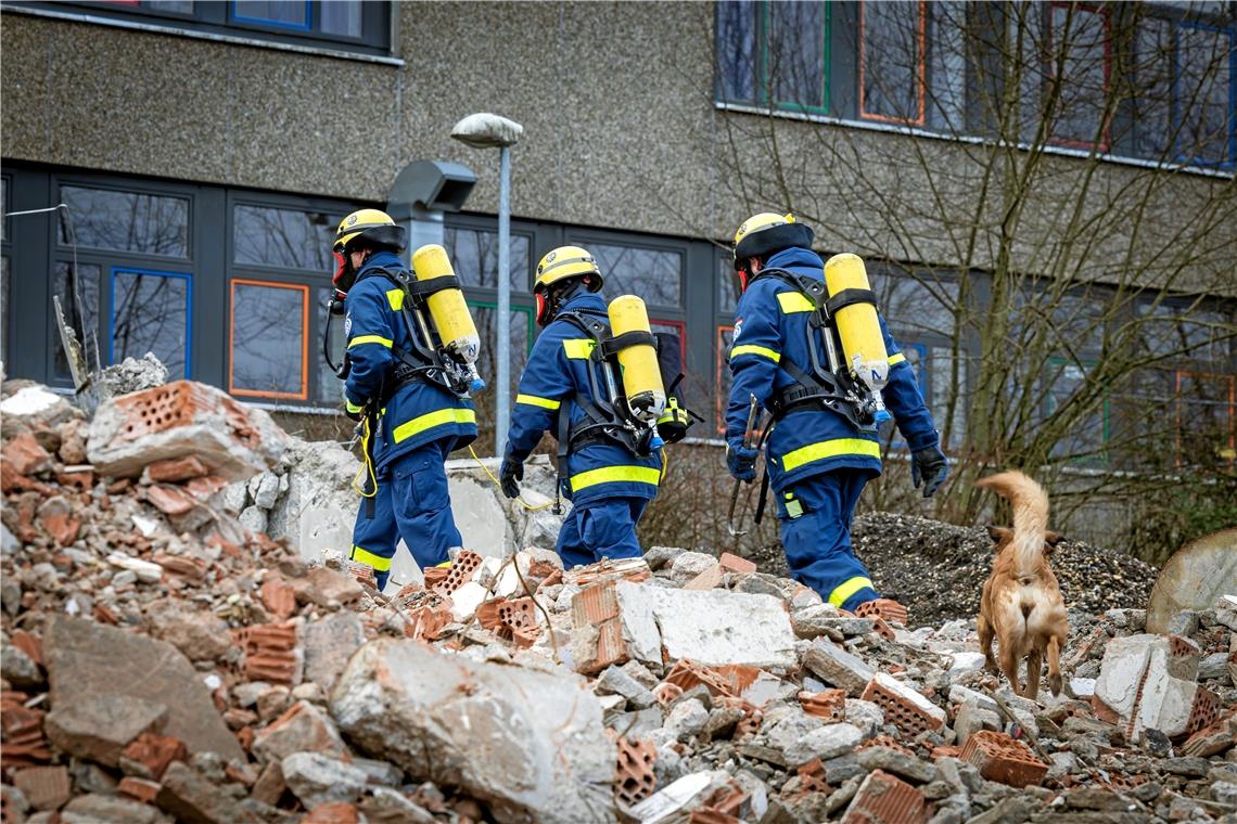 In Atemschutzausrüstung suchen die Helfer über die Trümmer einen Zugang zum Gebäude.