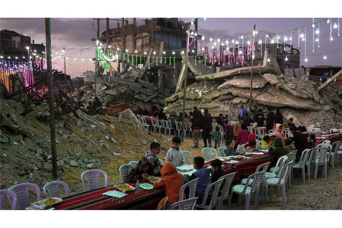 In Chan Junis sitzen Palästinenser an einem langen Tisch inmitten von zerstörten Gebäuden zum Fastenbrechen (Iftar) während des muslimischen heiligen Monats Ramadan.