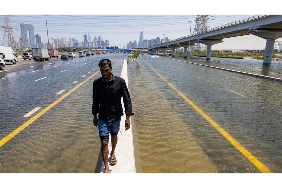 In den Vereinigten Arabischen Emiraten hat sich der heftigste Regen seit Jahrzehnten ereignet und Teile der Metropole Dubai überschwemmt. Ein Mann geht entlang einer Straßensperre auf der Sheikh Zayed Road.