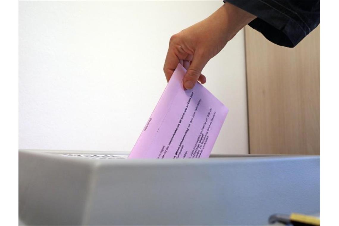 In der Briefwahlstelle steckt ein Wähler einen Umschlag in einen Kasten. Foto: Bernd Wüstneck/Archivbild