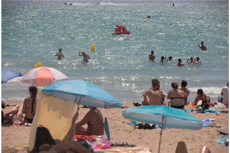 In der Hauptsaison ist es deutlich teurer: Menschen sonnen sich und schwimmen am Strand von Arenal auf Mallorca.