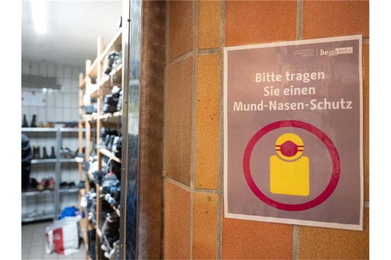 In der Kleiderkammer der Berliner Stadtmission hängt ein Plakat mit der Aufschrift „Bitte tragen Sie einen Mund-Nasen-Schutz“. Foto: Christophe Gateau/dpa