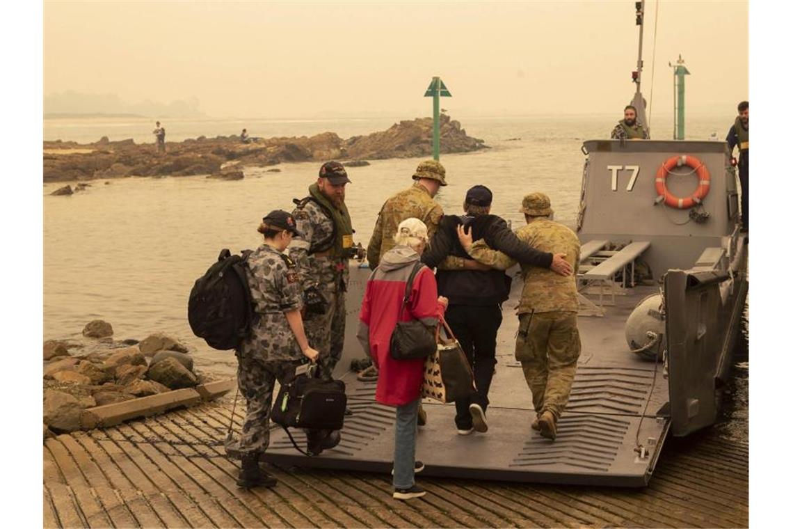 In der Küstenstadt Mallacoota bringt die Marine Menschen in Sicherheit, die sich an den Strand gerettet hatten. Foto: Pois Helen Frank/Royal Australian Navy/AP/dpa