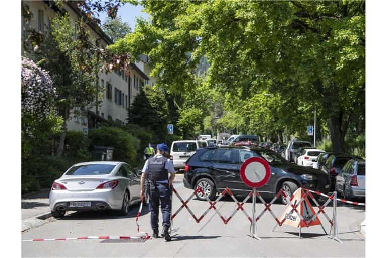 In der Nähe des Hauses wird die Straße, in dem es eine mutmaßliche Geiselnahme mit mehreren Toten gegeben hat, gesperrt. Foto: Ennio Leanza/Keystone