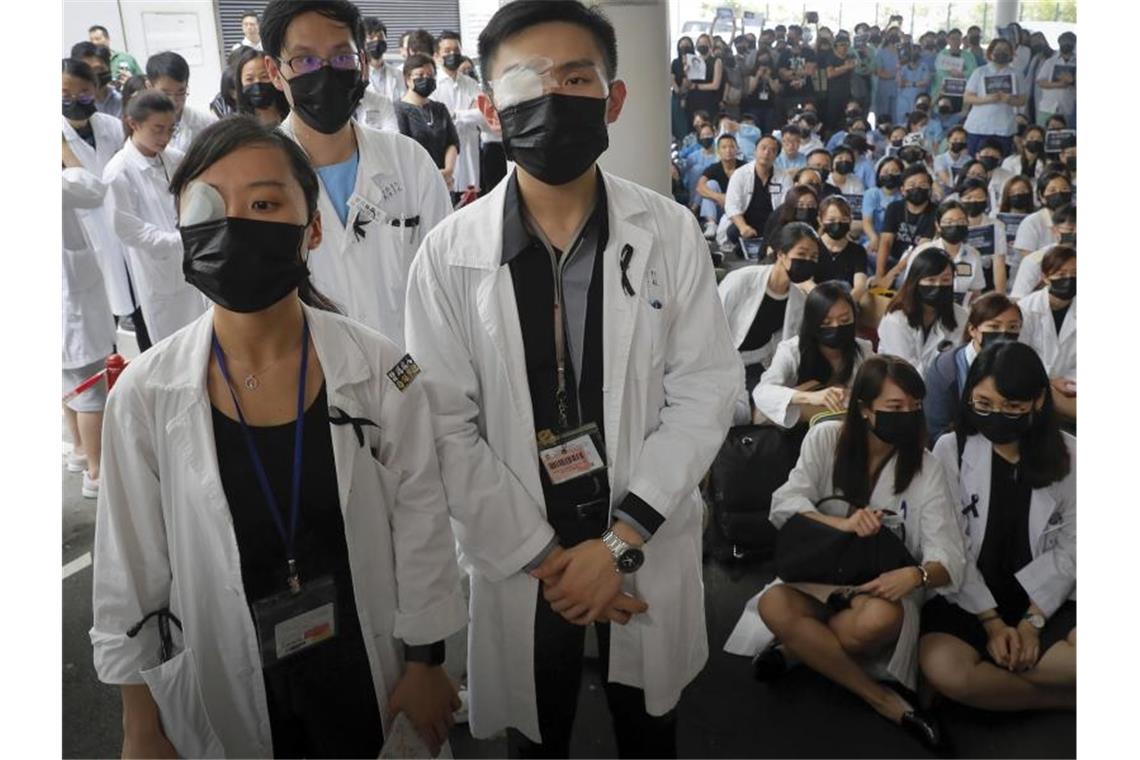 Heftige Zusammenstöße in Hongkongs Flughafen In einem Hongkonger Krankenhaus protestiert das Personal mit Augenklappe und Mundschutz gegen die Brutalität der Polizei gegenüber den Demonstranten. Foto: Kin Cheung/AP