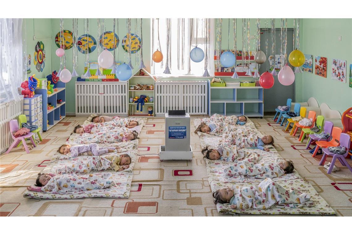 In einem Kindergarten in Ulaanbaatar, der Hauptstadt der Mongolei, liegen Kinder auf dem Boden um einen aufgestellten Luftfilter herum, der die Schadstoffkonzentration senken soll.