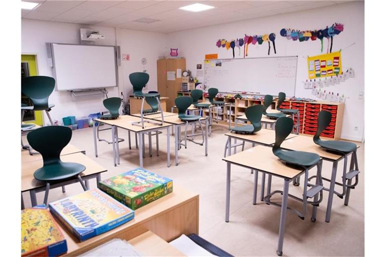 In einem Klassenzimmer stehen Stühle auf Tischen. Auf dem vordersten Tisch liegen Spiele aus. Foto: Christian Charisius/dpa/Archivbild