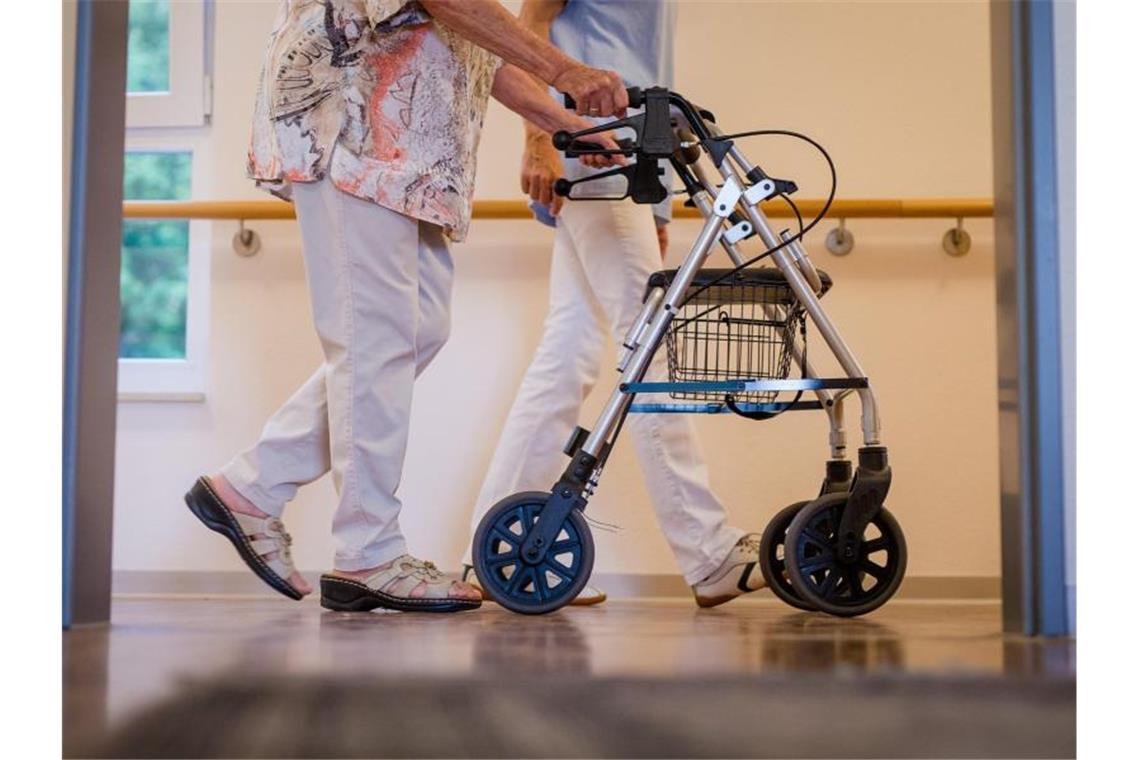 In einem Pflegeheim wird eine Bewohnerin von einer Pflegekraft begleitet. Foto: Christoph Schmidt