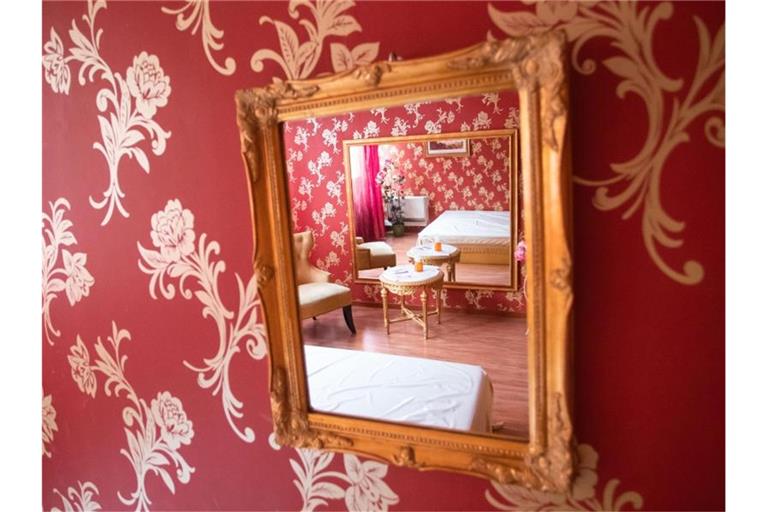 In einem Spiegel spiegelt sich ein Arbeitszimmer des Bordells „Lauras Girls“ in Karlsruhe. Foto: Tom Weller/dpa/Archivbild