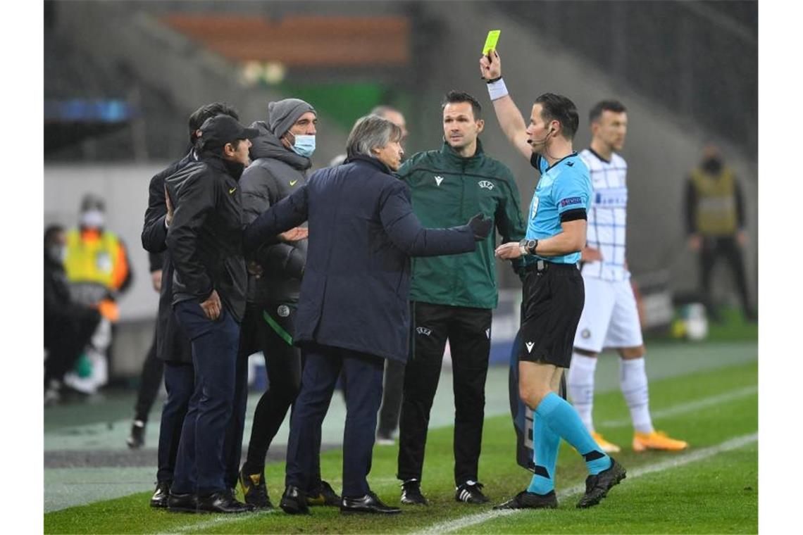 In einer hitzigen Schlussphase zeigt Schiedsrichter Danny Makkelie Mailands Trainer Antonio Conte (l) und Mönchengladbachs Trainer Marco Rose die Gelbe Karte. Foto: Marius Becker/dpa